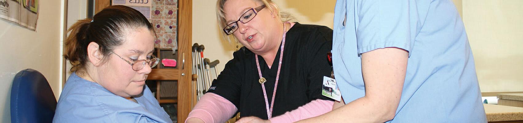 Phlebotomy instructor guiding student